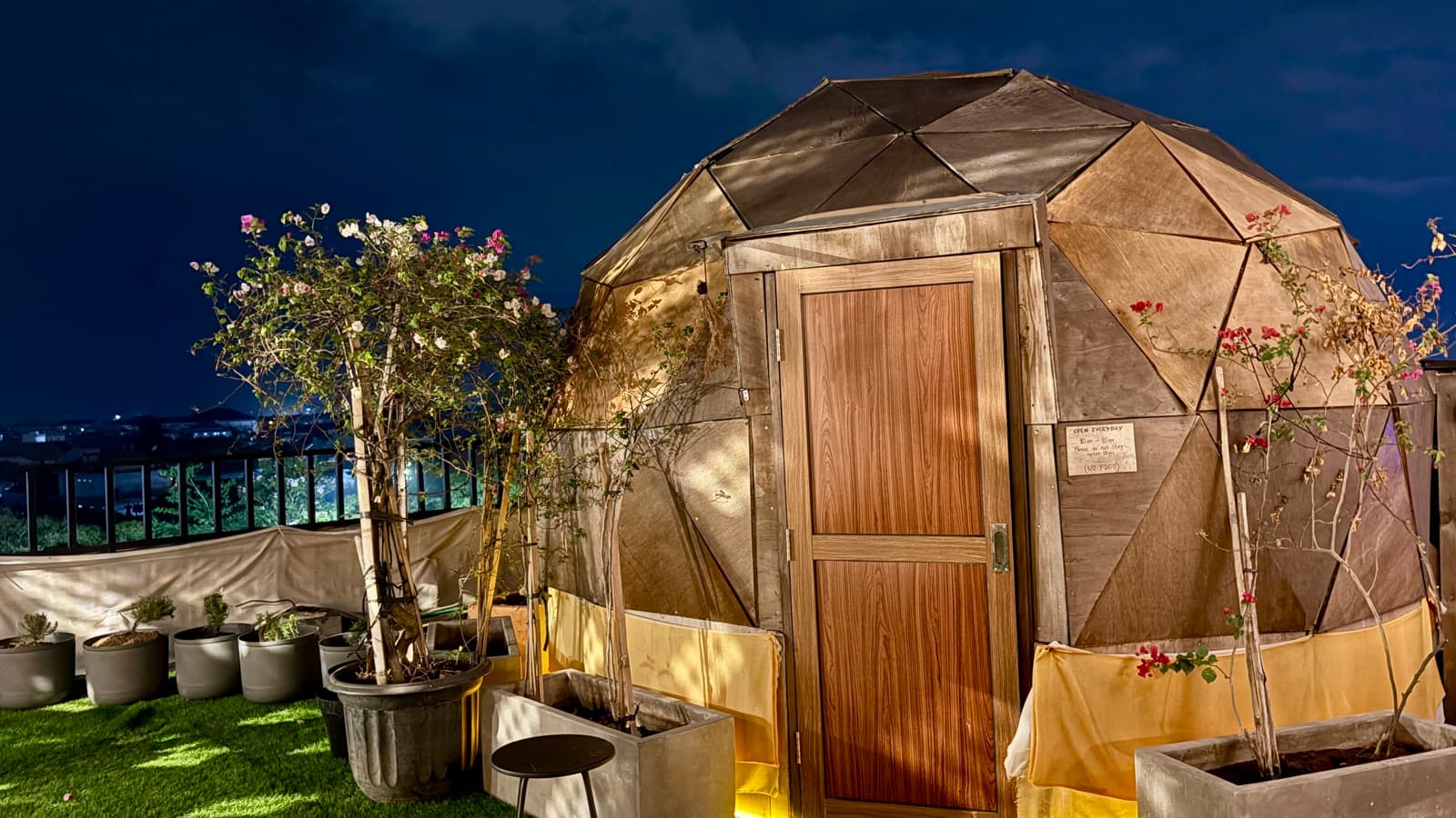 The dome sauna glowing at night, bougainvillea by the door