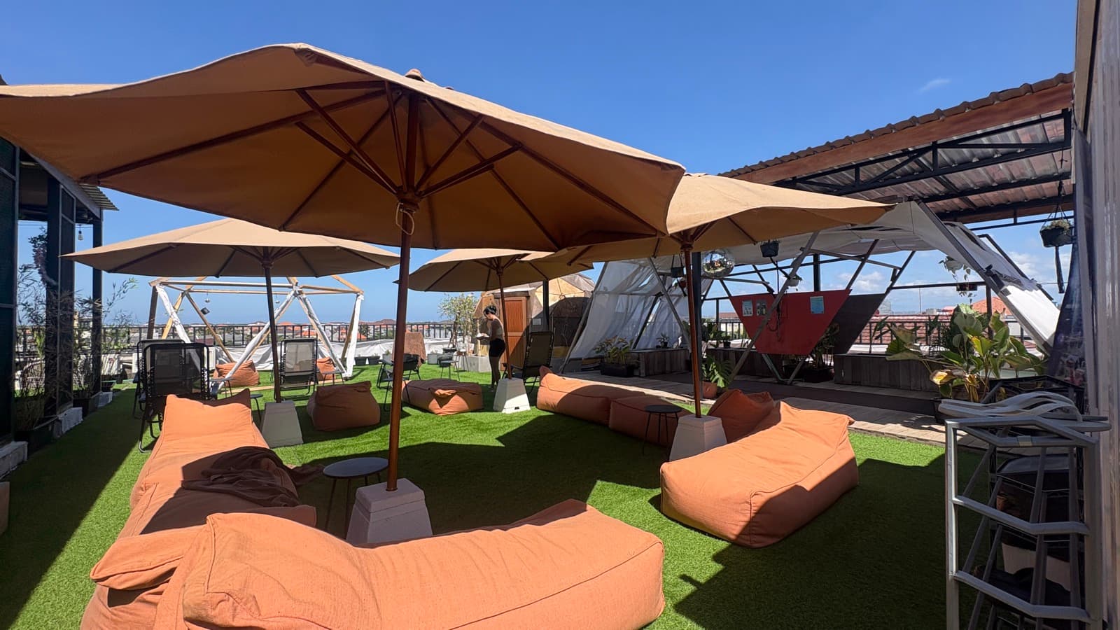 Umbrellas and beanbag loungers on the rooftop lawn, dome sauna behind